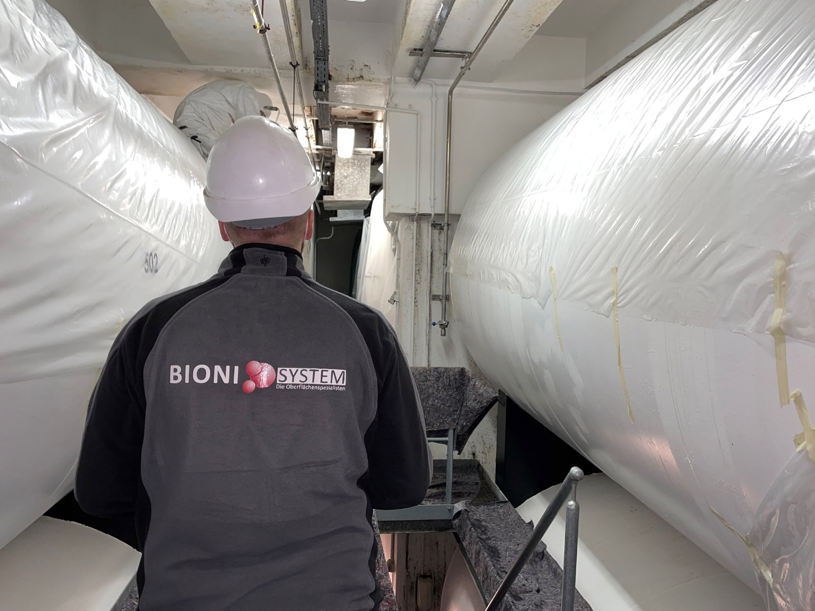 BioniSystem-Komplett-Leistungen_mobile Bioni System Mitarbeiter bei der Besichtigung mit dem Wort Komplett-Leistungen am unteren Rand