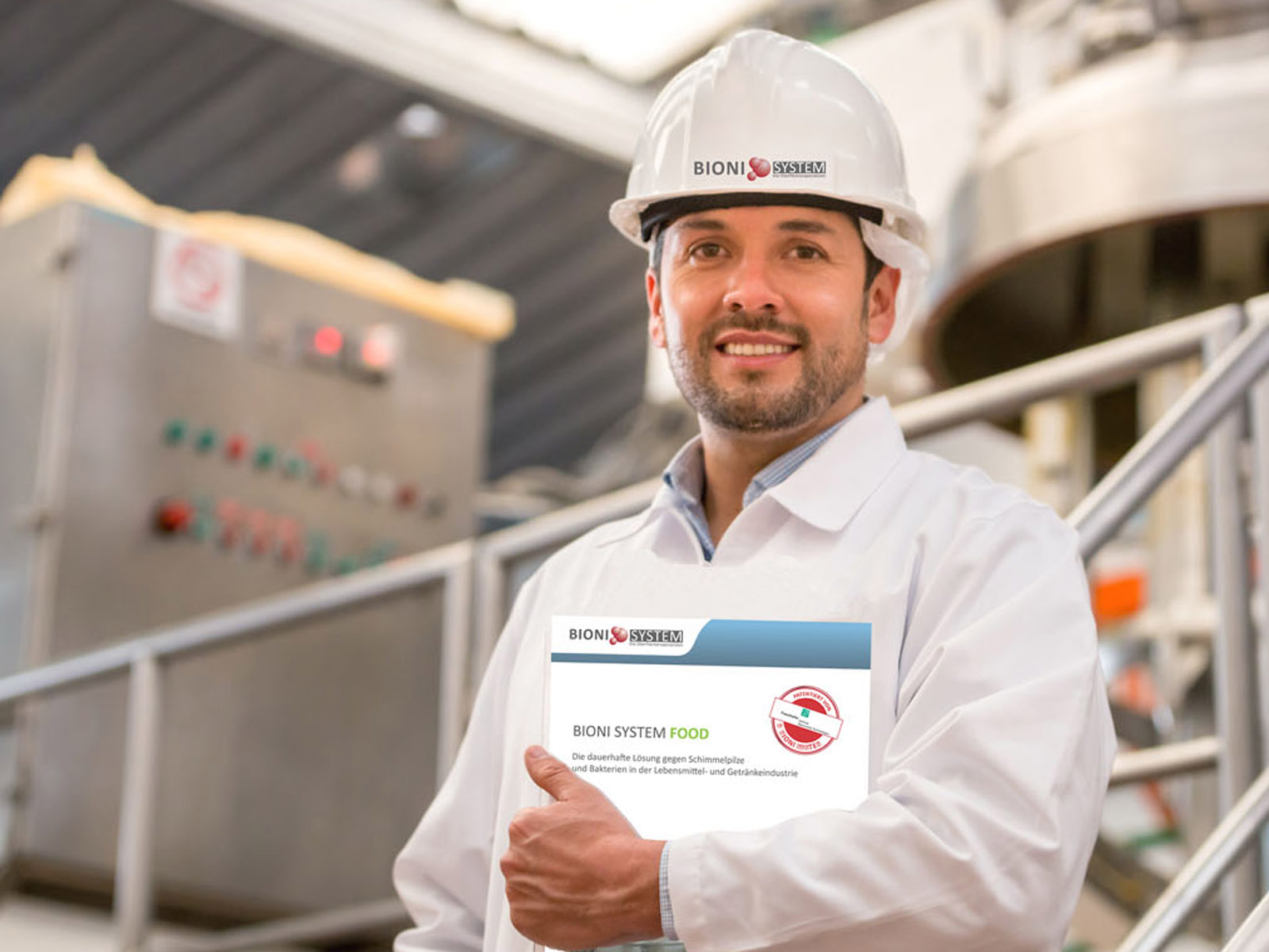 BioniSystem_Branchen_Food_3 Bioni System Mitarbeiter mit Broschüre und Helm an einer Anlage eines Lebensmittelherstellers